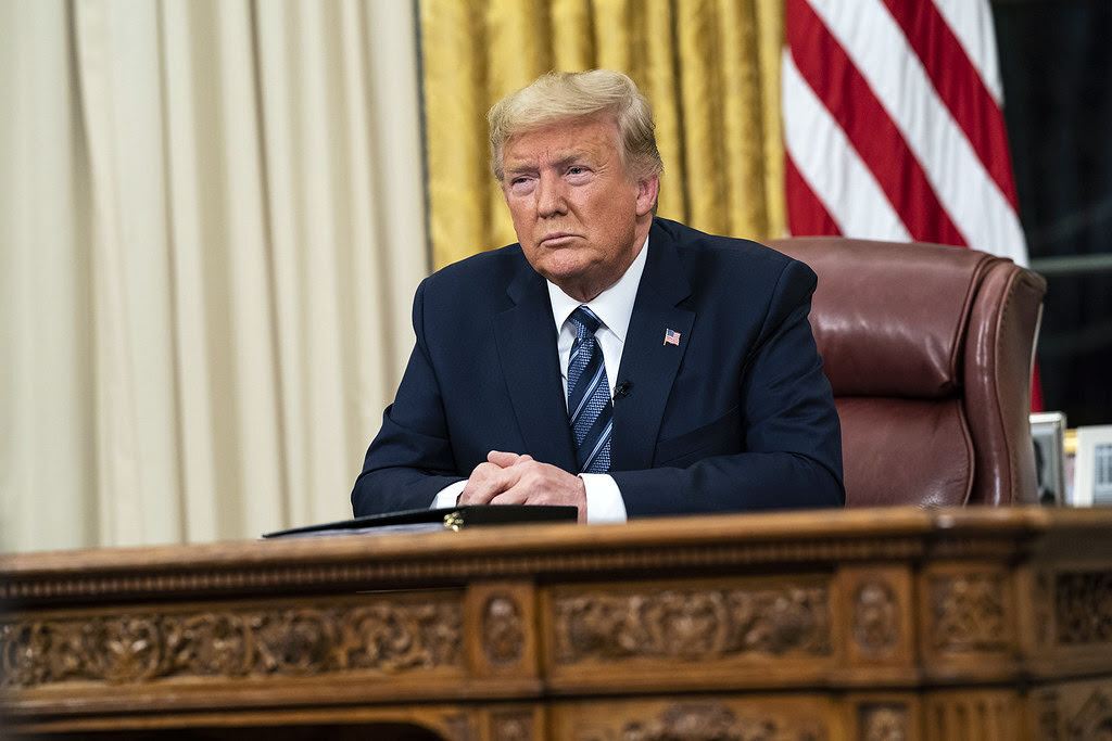 Donald Trump seated behind the Resolute Desk in the Oval Office