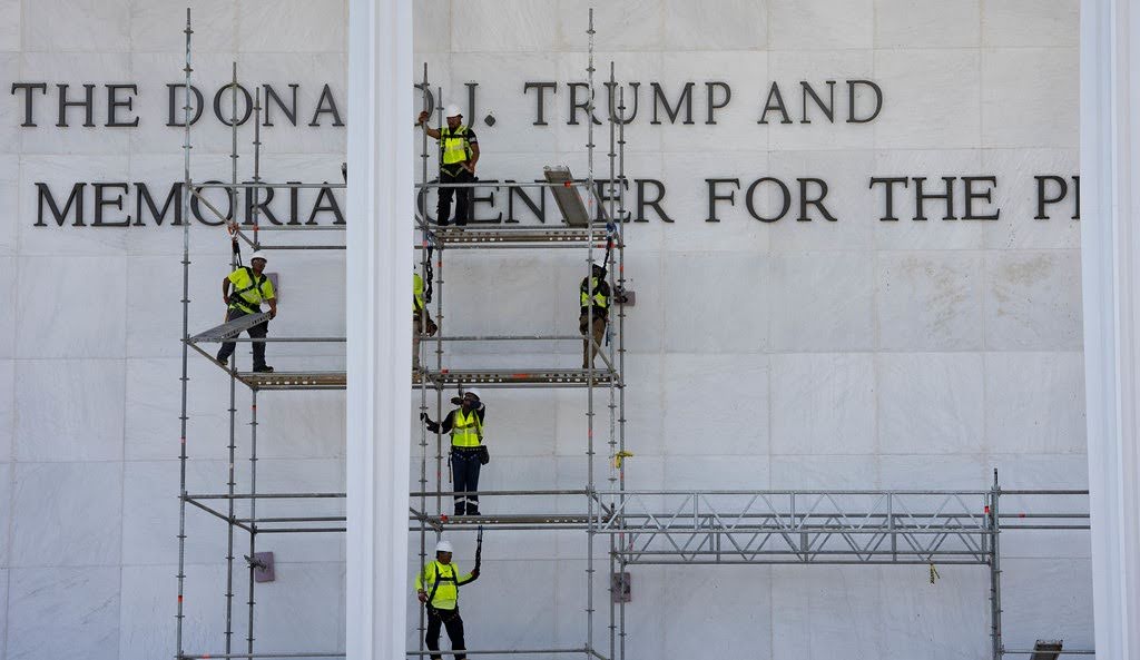Workers on scaffolding installing the Donald J. Trump inscription across the front of the Kennedy Center
